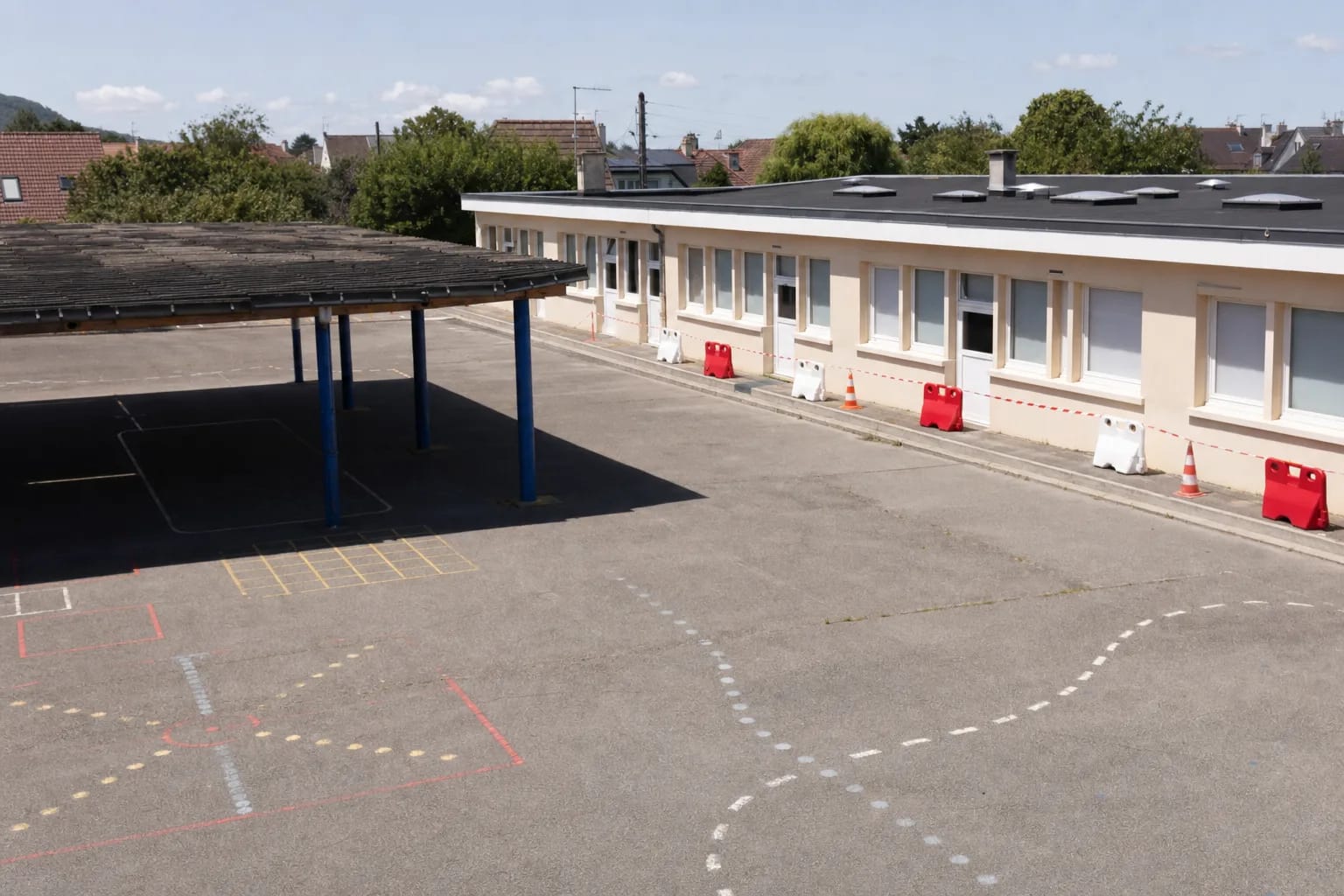 Patio escolar vacío durante las vacaciones con acceso de obra señalizado